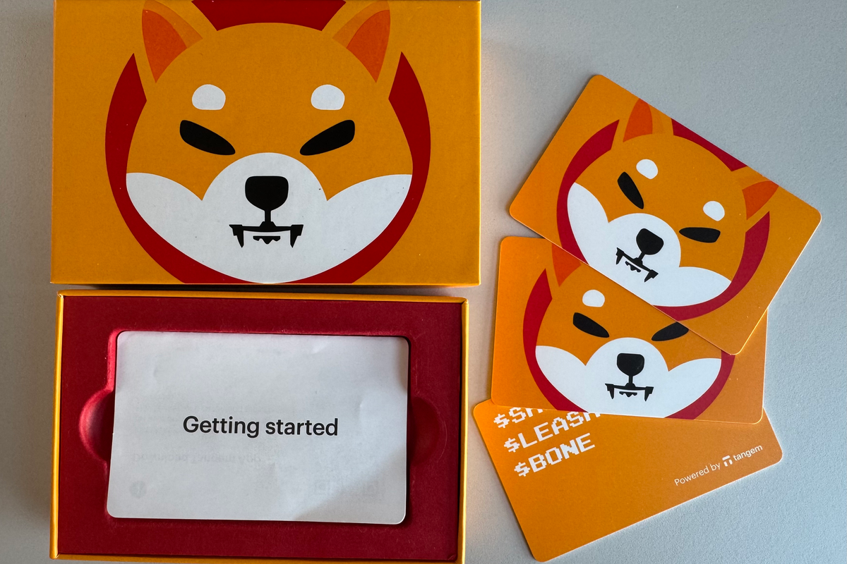 Three Tangem wallet NFC cards laid out with packaging and quick-start guide